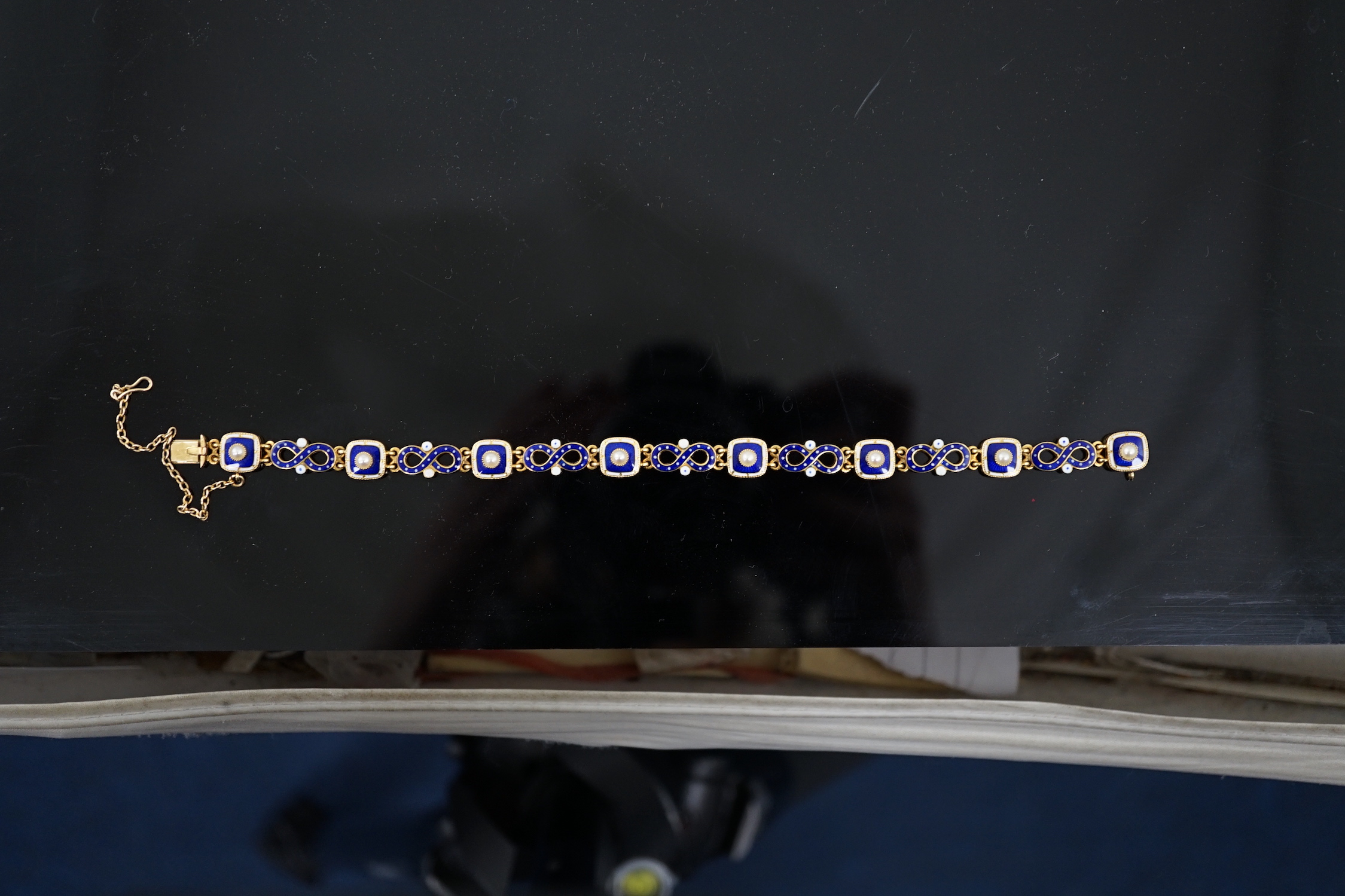 An early 20th century gold (tests as 18ct), two colour enamel and spilt pearl set bracelet